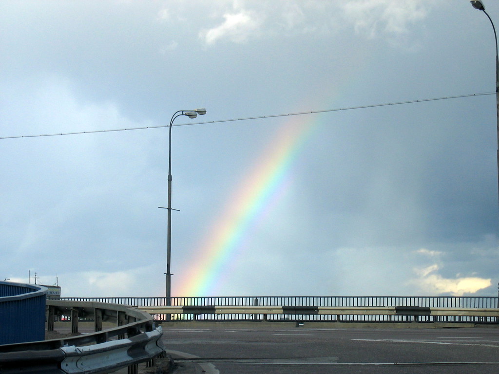 Arcobaleno che sembra fermato da un traliccio elettrico