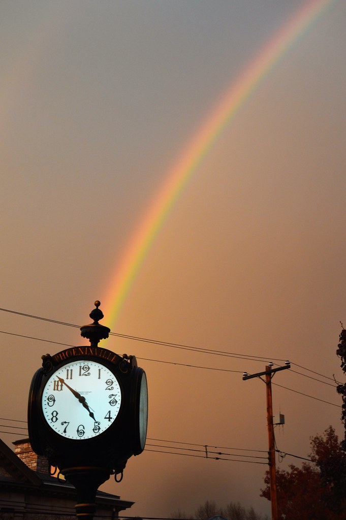 Arcobaleno che sembra nascere da un grande orologio esterno