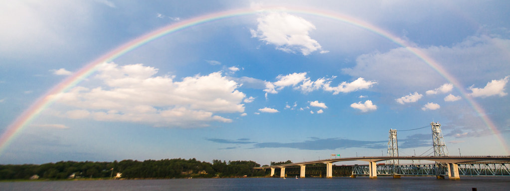 Arcobaleno che sembra storto a causa di prospettiva e ponte