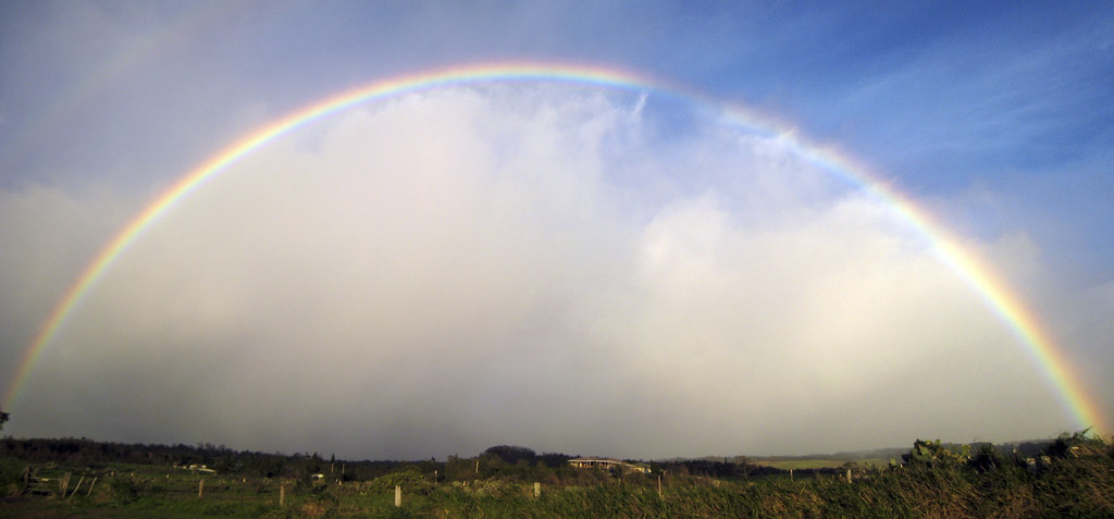 Arcobaleno intero con bella nuvola bianca di sotto