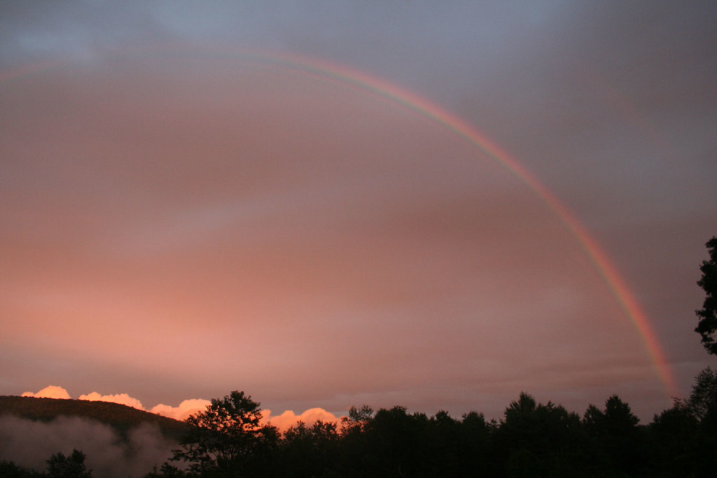 Arcobaleno rossastro che sembra illuminare il cielo di rosso