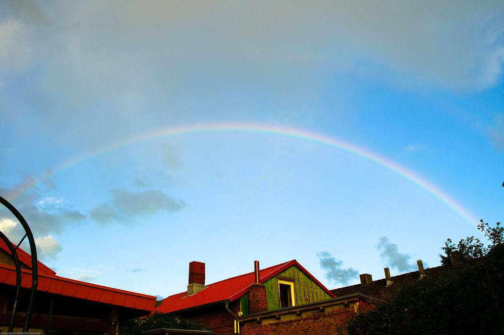 Arcobaleno sottile sopra bella casa rossa