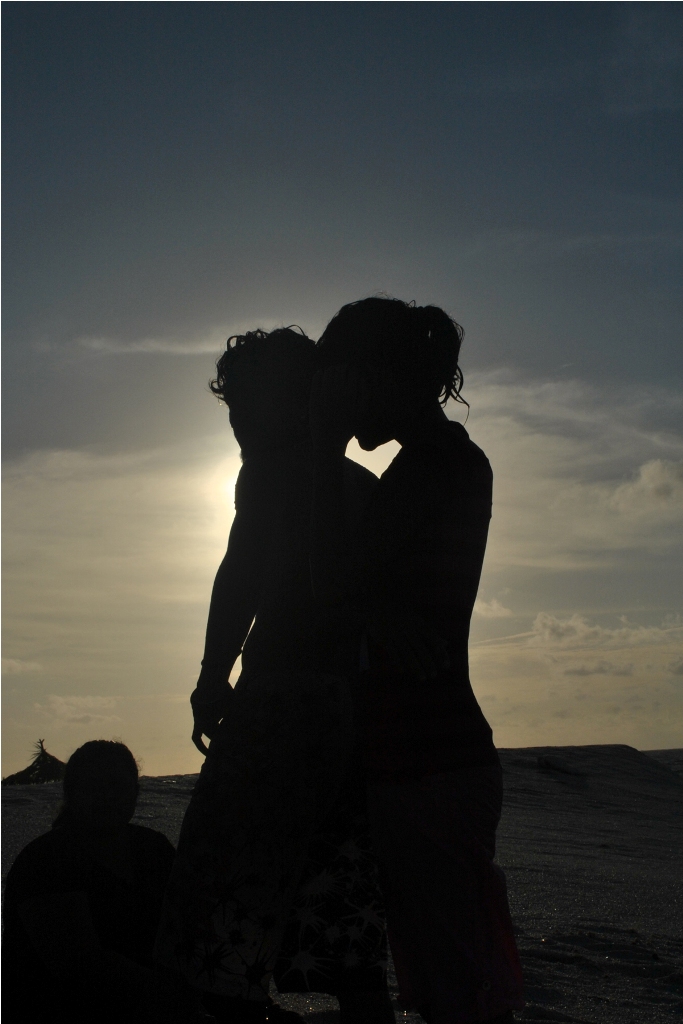 Bacio romantico sulla spiaggia al calar della sera