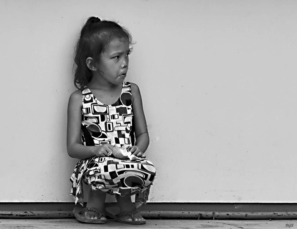 Bambina con broncio accovacciata in bianco e nero