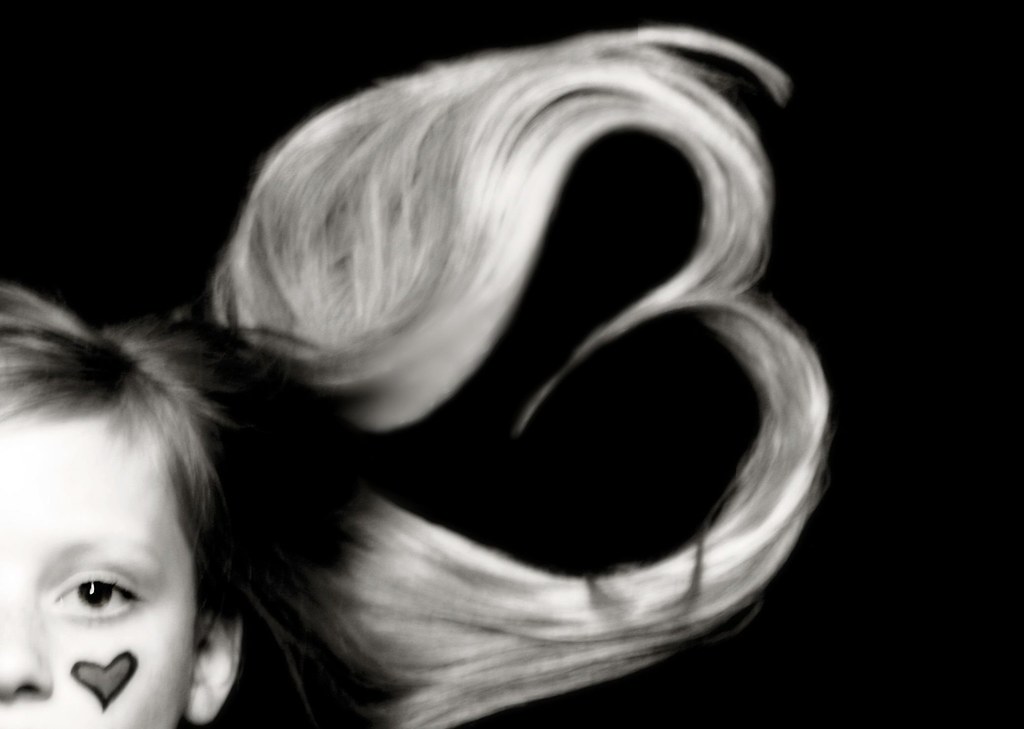 Bambina con tatuaggio di cuore e con capelli disposti a cuore