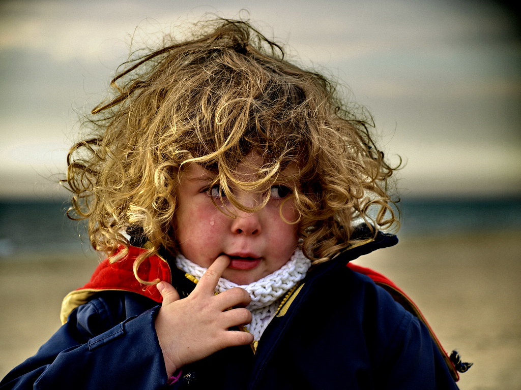 Bambino con capelli molto voluminosi con dito in bocca