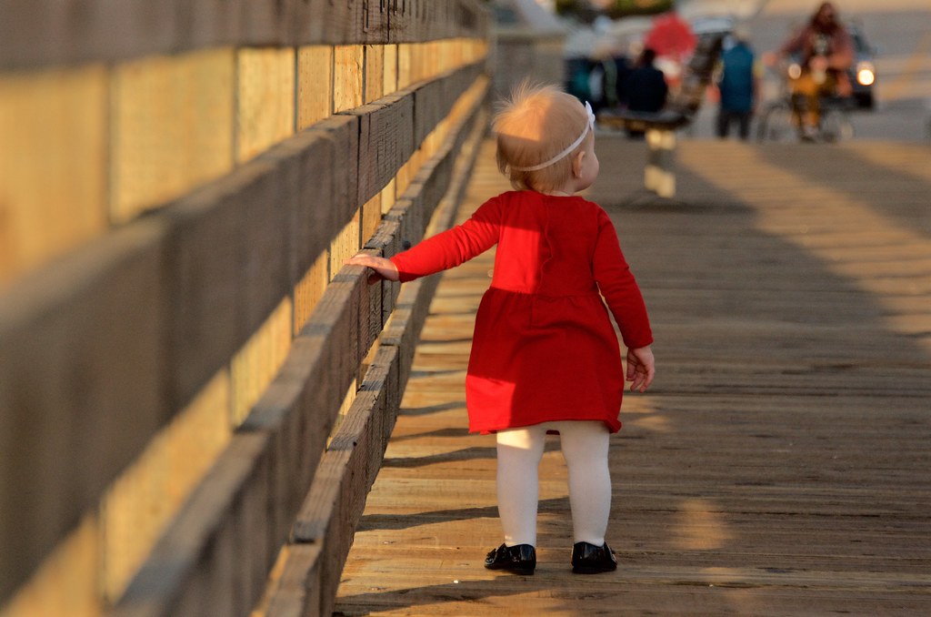 Bimba con vestito rosso che cammina per esplorare il mondo