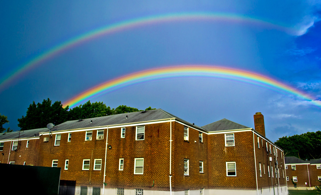 Doppio arcobaleno in bel cielo blu che sovrasta case americane