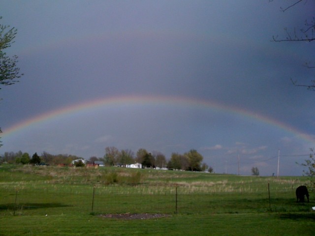 Doppio arcobaleno in cielo blu sopra campagna