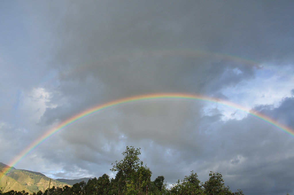 Doppio arcobaleno in cielo nuvoloso tendente al celestino