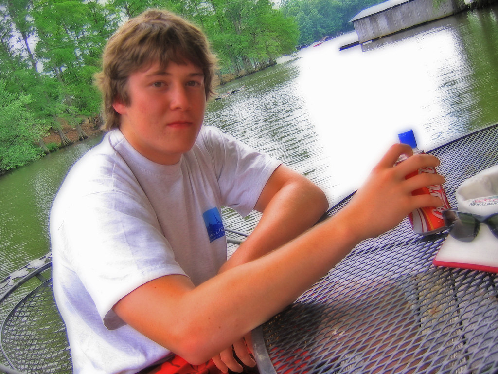 Giovane ragazzo in maglietta a tavola al lago in estate
