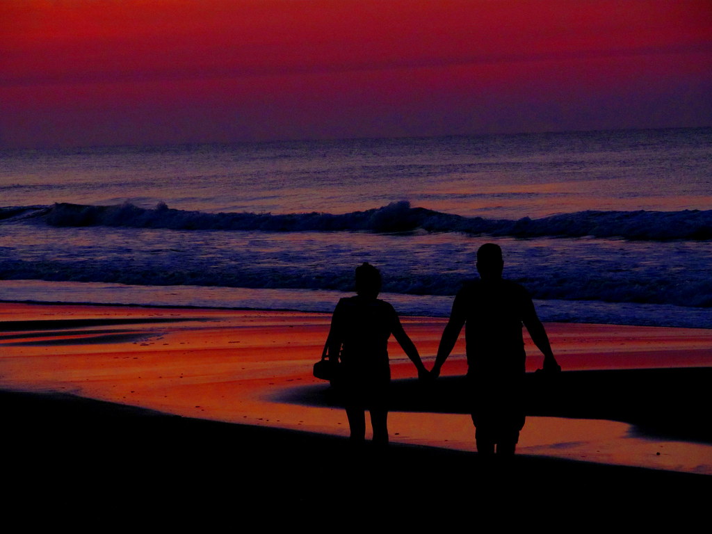 Insieme mano nella mano sulla spiaggia al tramonto