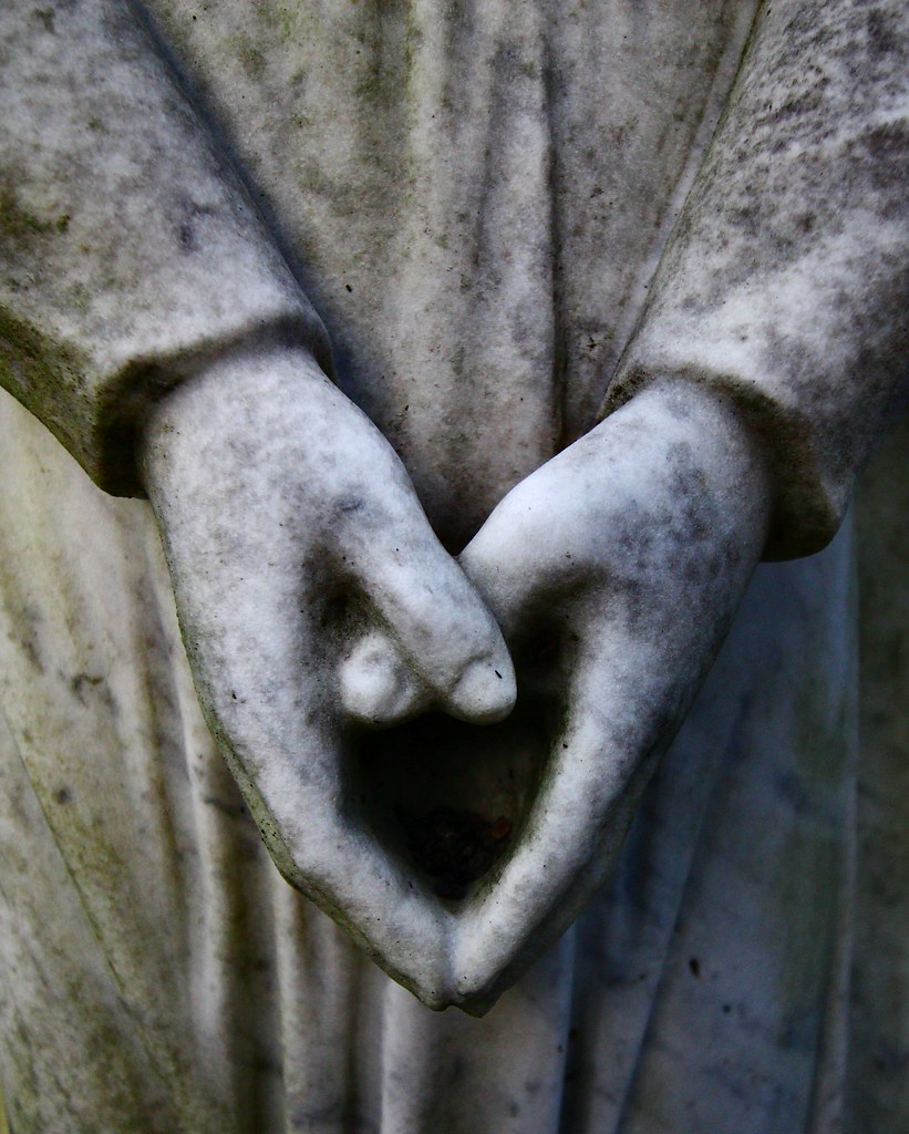 Mani basse di statua unite a formare un cuore
