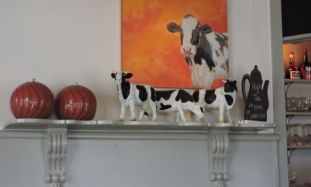 Mucche souvenir su mensola con dietro il quadro di una mucca