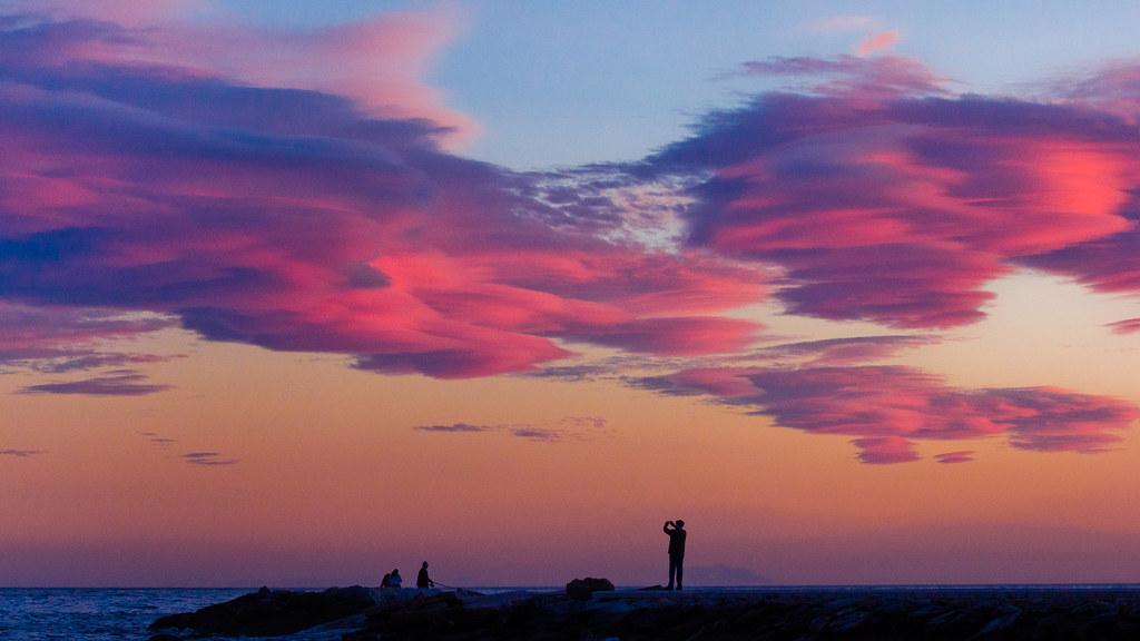 Persone in lontananza con cielo immenso al tramonto