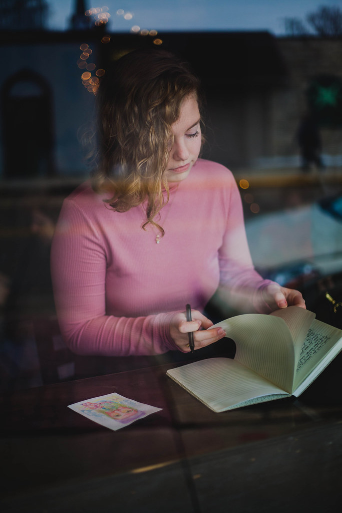 Ragazza con bei capelli ricci di lato che sfoglia un libro