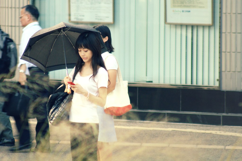 Ragazza giapponese con telefonino rosso e ombrello