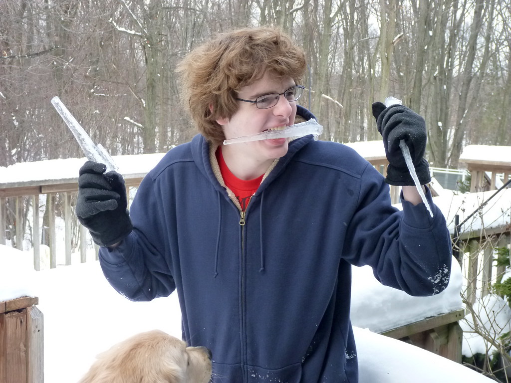 Ragazzo con capigliatura folta e occhiali in paesaggio nevoso