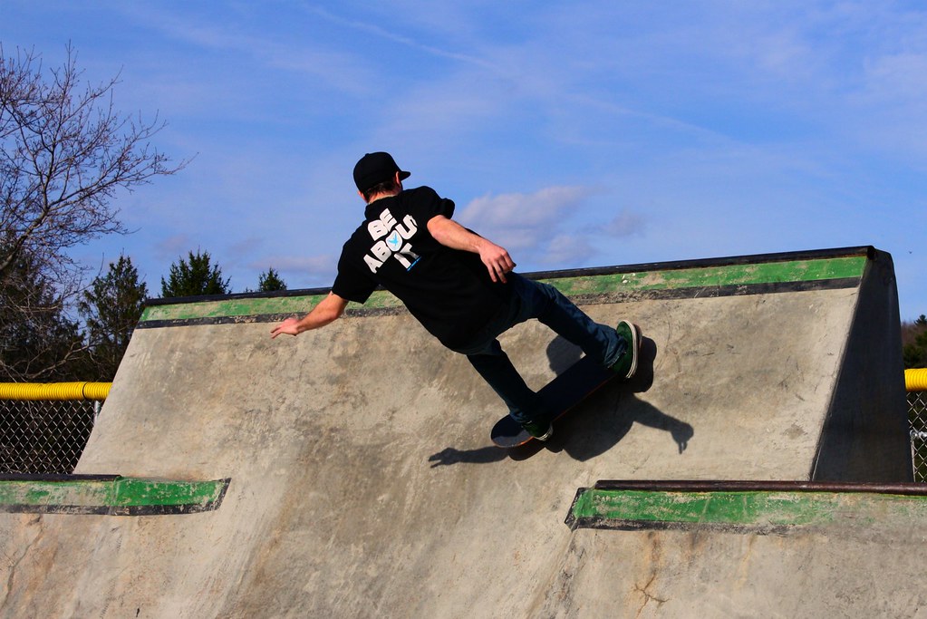 Ragazzo con skateboard impegnato a fare skate in skatepark