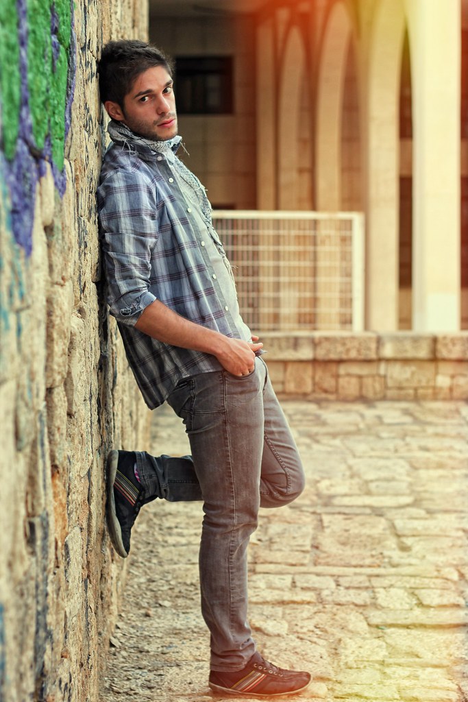 Ragazzo con vestiti casual in posa da modello adagiato su muro