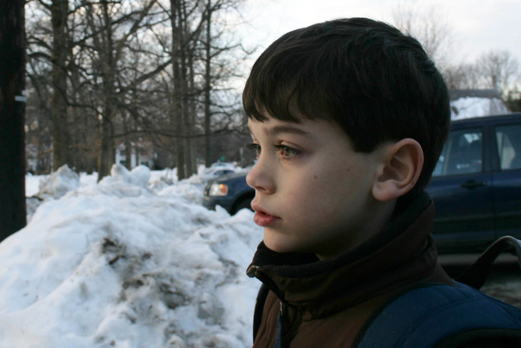 Ragazzo di profilo in freddo paesaggio innevato