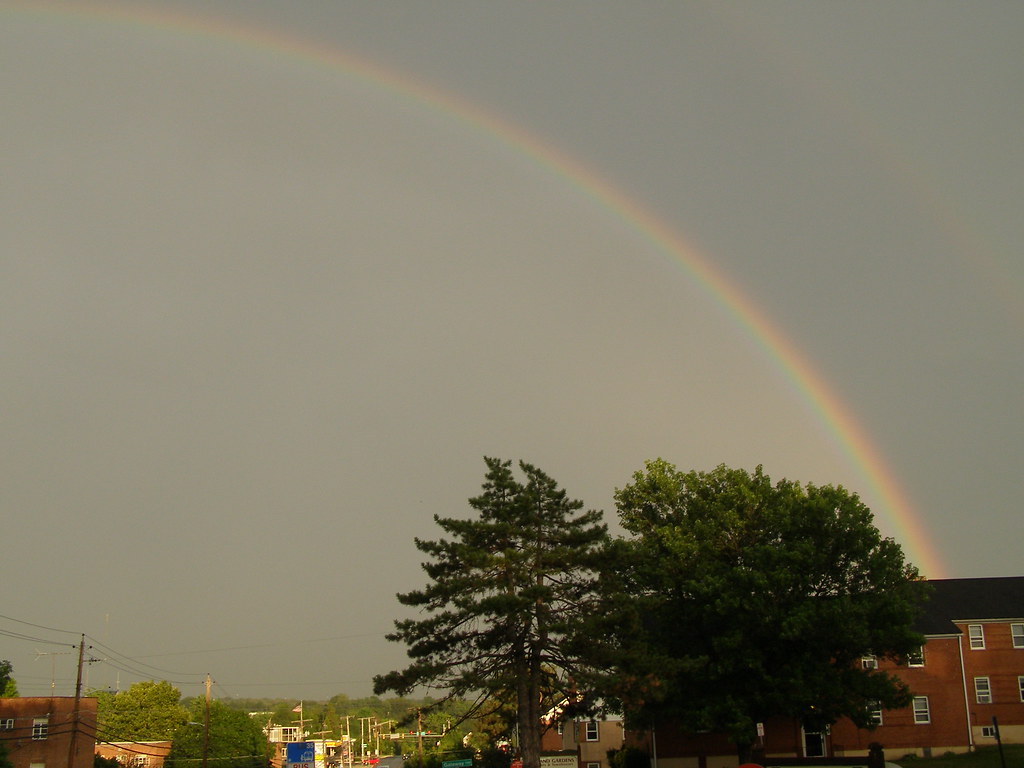 Semiarco di arcobaleno che parte dietro una casa