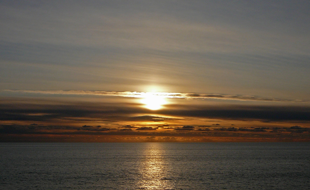 Sole basso nel cielo che si riflette sul mare