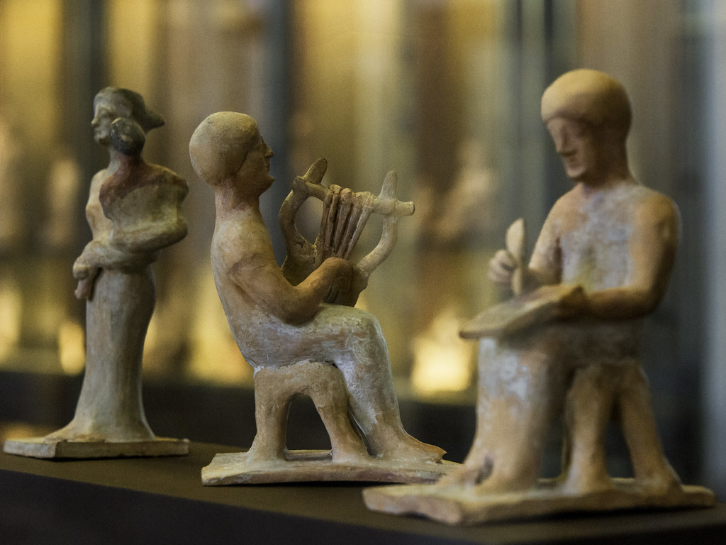 Tre statuine di cui una raffigura un uomo che suona la lira