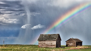 Arcobaleno sopra casotte nel verde