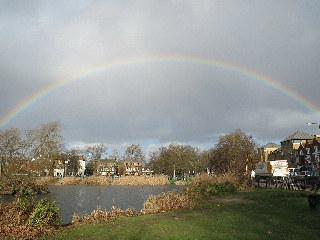 Arcobaleno sopra laghetto circondato dal verde