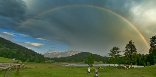 Arcobaleno sopra prato tra montagne verdi