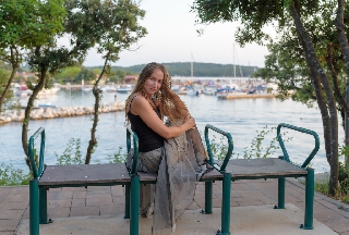 Bella ragazza seduta su panchina con tanti posti in Croazia