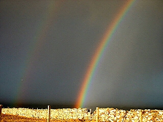 Doppio arcobaleno dietro muretto chiaro