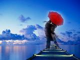 Abbraccio tra innamorati sotto ombrello rosso