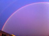 Arcobaleno che riempie un cielo viola in diagonale