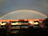 Arcobaleno che sembra abbracciare grossa palazzina