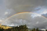 Arcobaleno doppio sopra alberi con dietro montagne