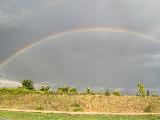 Immagine terreno Arcobaleno in cielo grigio sopra terreno erboso