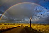 Arcobaleno in cielo nuvoloso blu sopra terra gialla