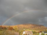 Arcobaleno in cielo nuvoloso sopra paesaggio rurale