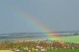 Arcobaleno tenue sopra piccola cittadina immersa nel verde