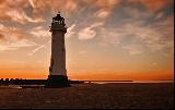 Bellissimo faro investito dalla luce arancione del tramonto