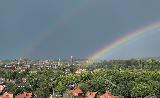 Doppio arcobaleno alto nel cielo sopra piccola città