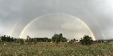 Doppio arcobaleno fantastico molto luminoso in cielo plumbeo