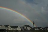 Doppio arcobaleno in cielo plumbleo sopra diverse villette