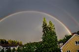 Immagine doppio Doppio arcobaleno sopra alberi irti e tetti di case