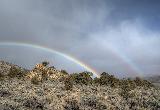 Immagine doppio Doppio arcobaleno sopra terreno roccioso
