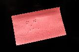 Faccina triste disegnata su foglio rosa con sfondo nero