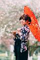 Immagine kimono Giapponese in kimono al parco con ombrellino arancione