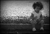 Incantevole bambina seduta in bianco e nero